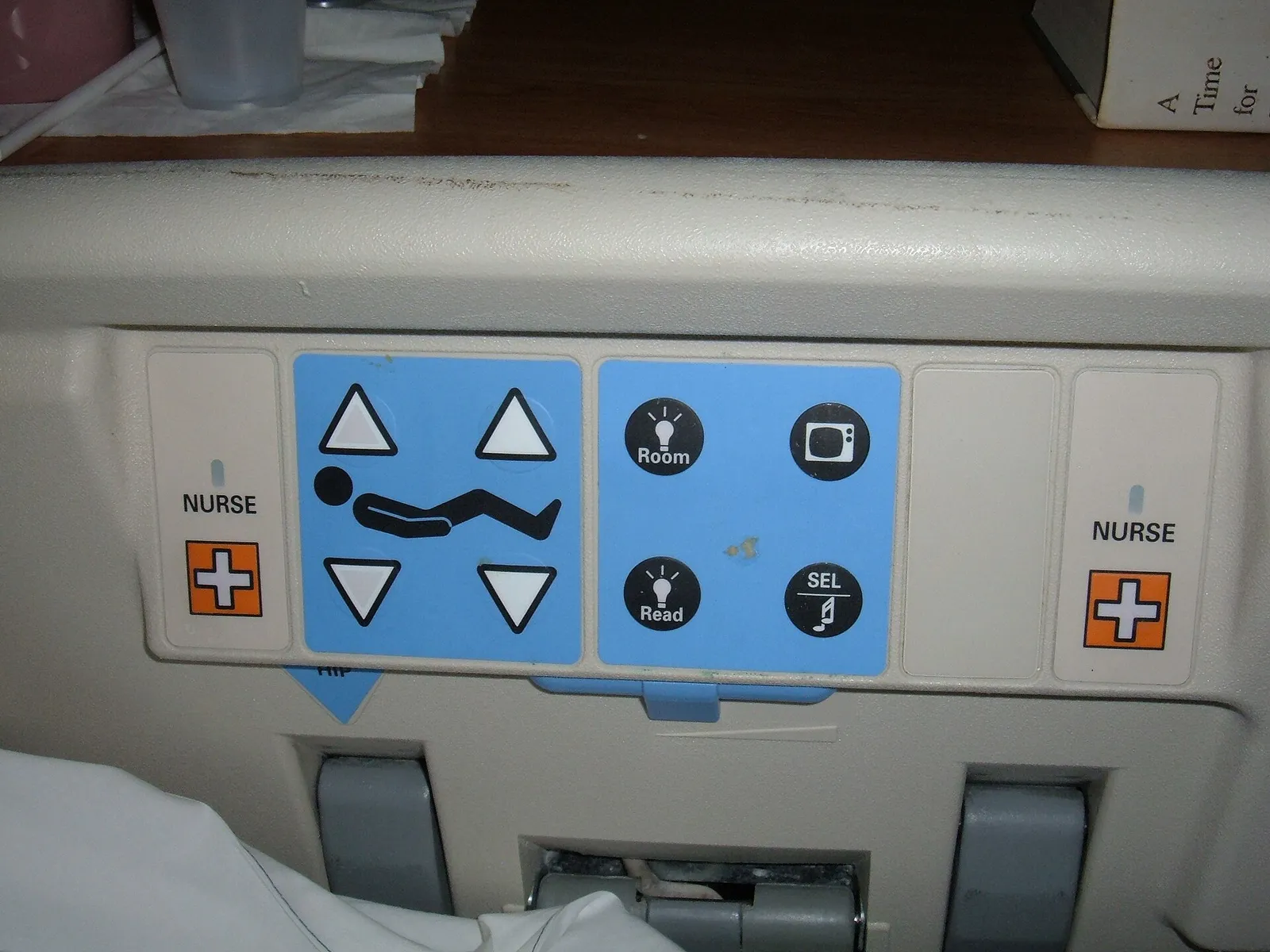 Patient in a hospital bed holding a nurse call handset with call and light buttons