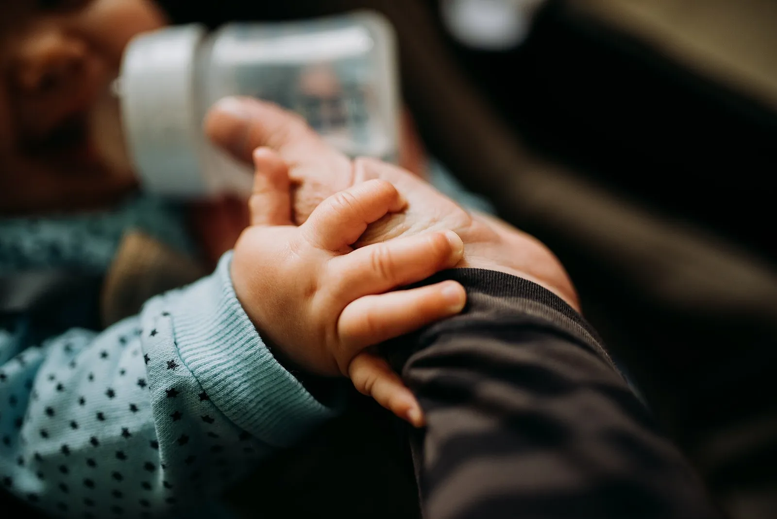Close-up of a caregiver's hand holding a smartphone showing an incoming alert, hospital corridor blurred behind