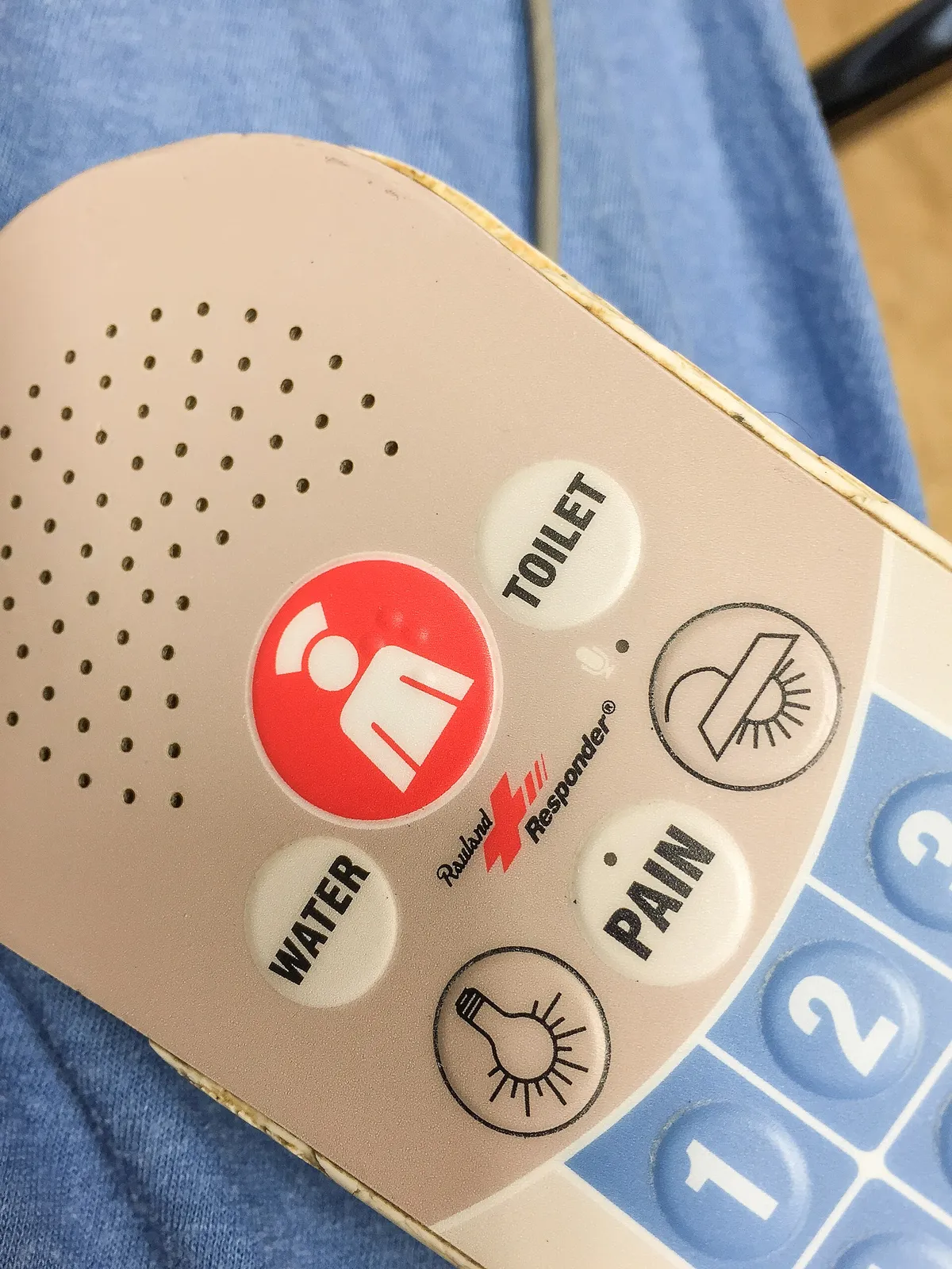 Nurse call patient station mounted on the wall beside a hospital bed
