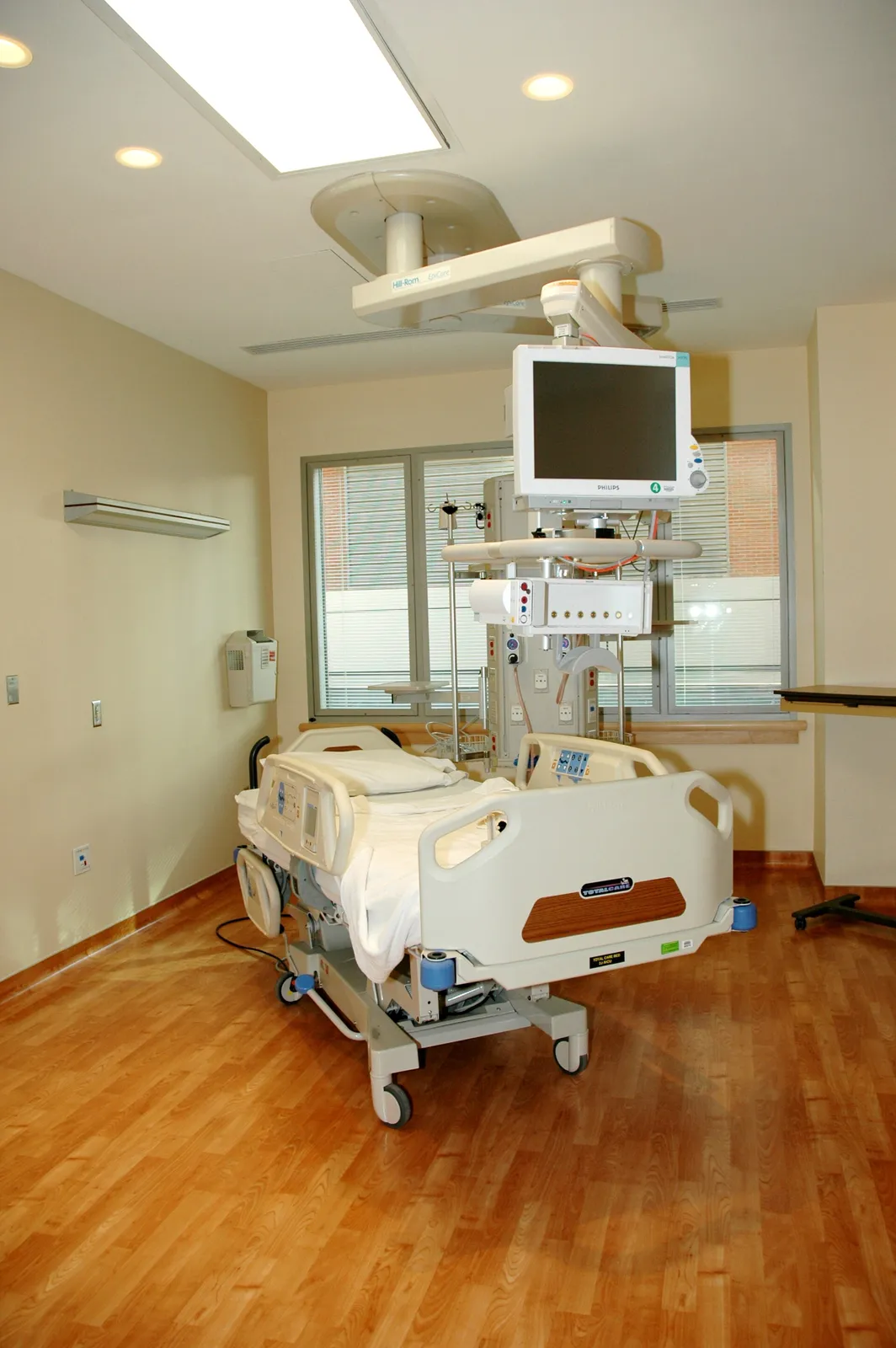 Hospital patient room with a bedside nurse call handset clipped to the bed rail