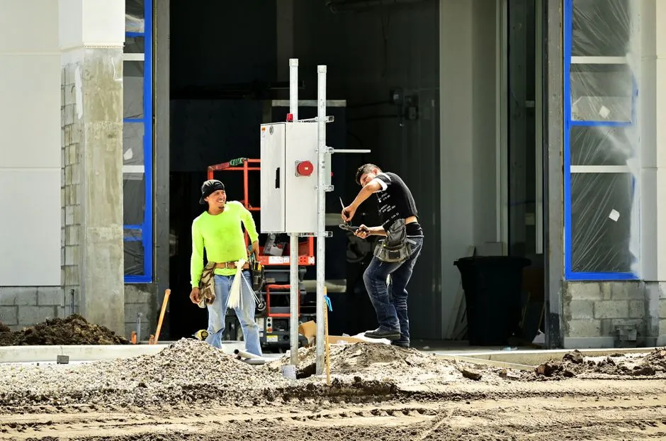 Electrician running nurse call cabling through wall studs on a hospital construction site