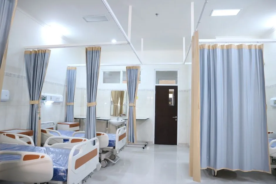 Stripped-out hospital ward under refurbishment with exposed ceiling and new bedhead units on the wall