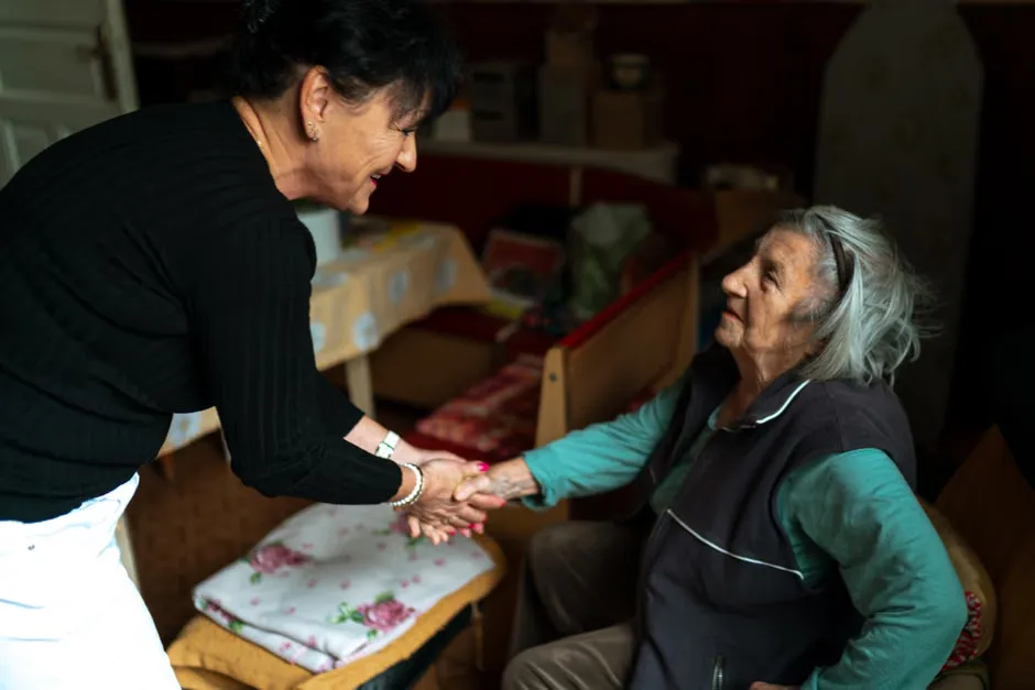 Caregiver in an aged care corridor reading an alert on a mobile handset